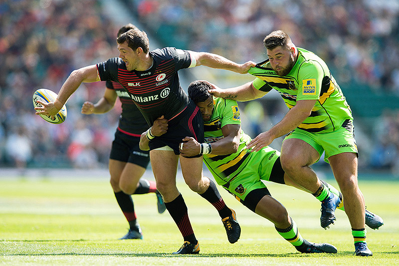 Alex Goode of Saracens offloads the ball after being tackled